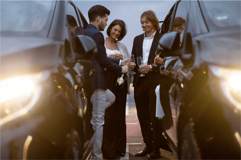 Couples celebrating next to their elegant transport, raising glasses in a toast, embodying the joy and luxury of special event transportation.